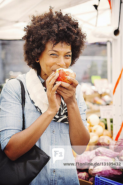 Portrait of woman eating apple in market
