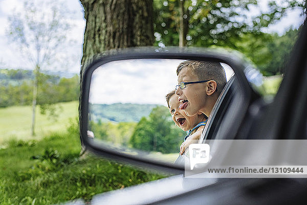 Nahaufnahme von Geschwistern  die im Seitenspiegel eines Autos reflektieren