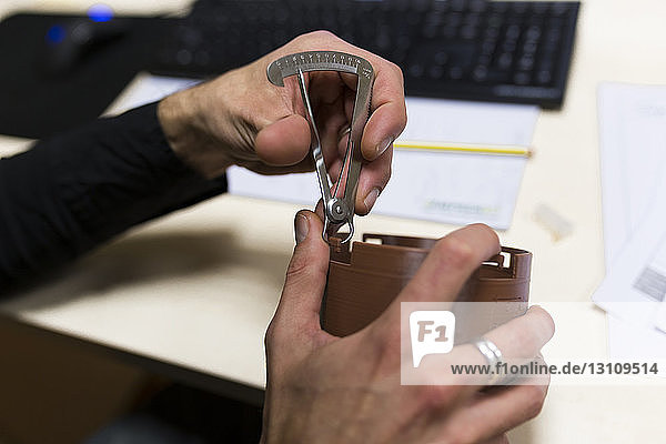 Beschnittene Hände eines männlichen Ingenieurs  der an einem 3D-Druckentwurf arbeitet