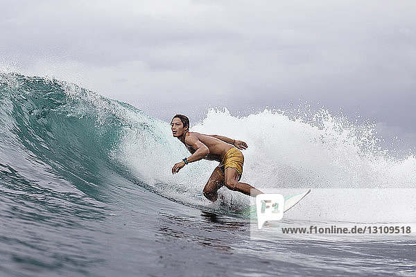 Engagierter junger Mann surft auf dem Meer