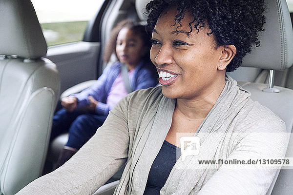 Glückliche Frau schaut weg  während sie mit ihrer Tochter im Auto unterwegs ist