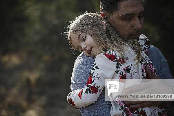 Vater trägt Tochter auf dem Feld