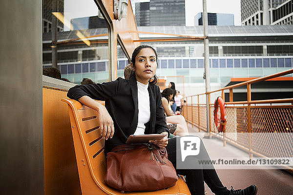 Nachdenkliche Frau benutzt digitales Tablet  während sie in der Stadt auf einer Bank sitzt