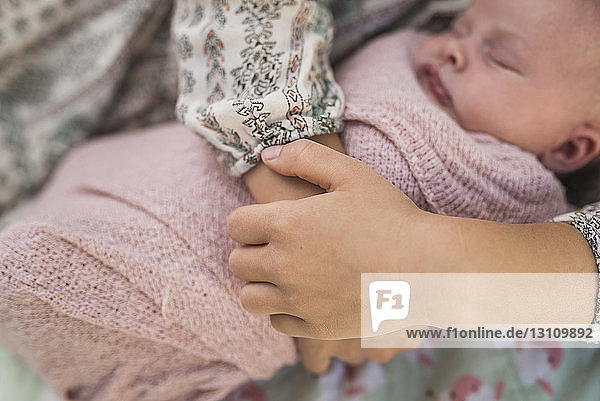 Cropped hands of sister holding newborn baby