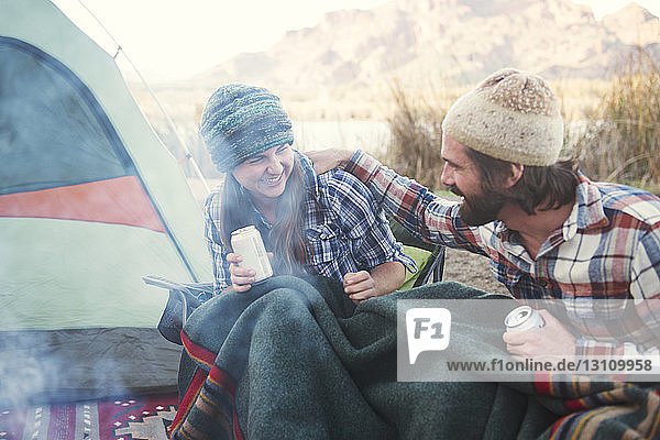 Glückliches Paar hält Bierdosen in der Hand und genießt auf dem Campingplatz