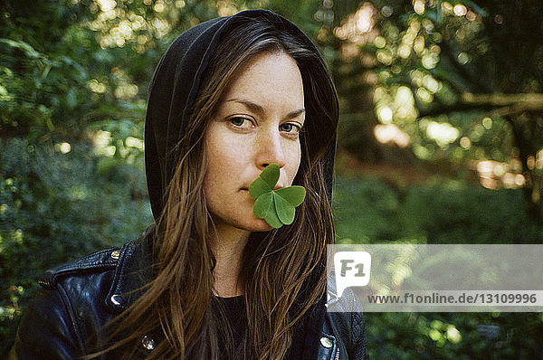 Portrait of woman with clover leaves in mouth in forest