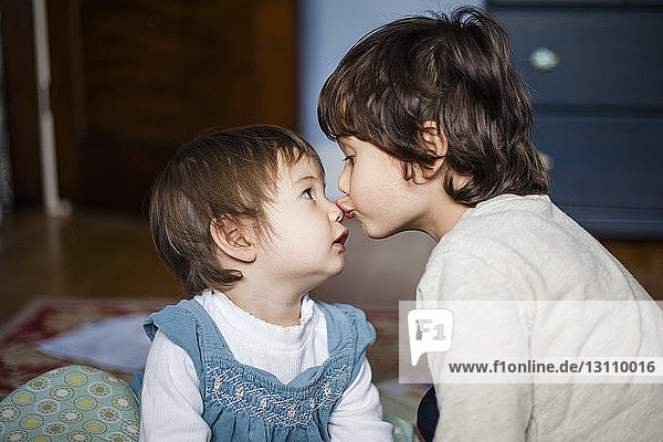 Nahaufnahme eines Bruders  der seine niedliche Schwester zu Hause auf die Nase küsst