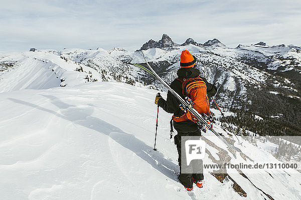 Rear view of hiker with backpack and ski standing on snowcapped mountain