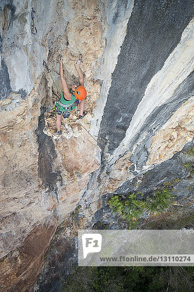 Rear view of female hiker rock climbing
