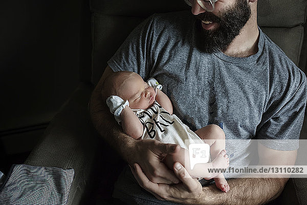 Father carrying sleeping newborn son at home