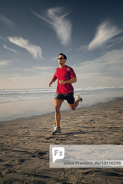 Entschlossener Sportler läuft in voller Länge am Strand