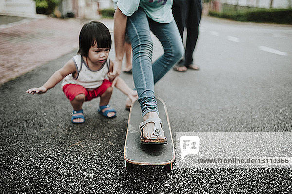 Junge sieht Schwester beim Skateboarden auf der Straße