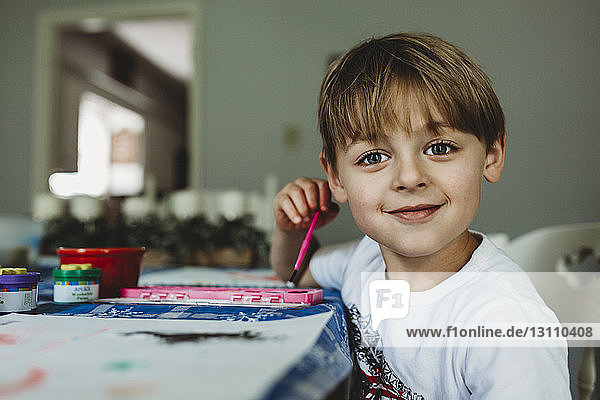 Porträt eines selbstbewussten Jungen  der zu Hause auf dem Tisch malt
