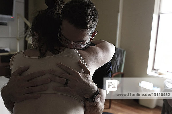 Mann umarmt schwangere Frau auf Krankenhausstation