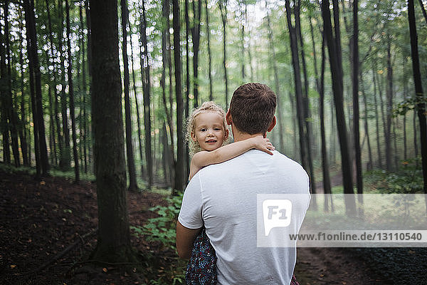 Portrait of daughter carried by father at forest