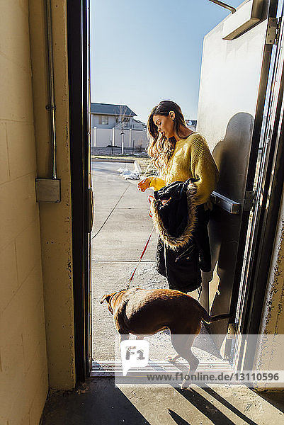 Seitenansicht einer am Eingang stehenden Frau mit Hund