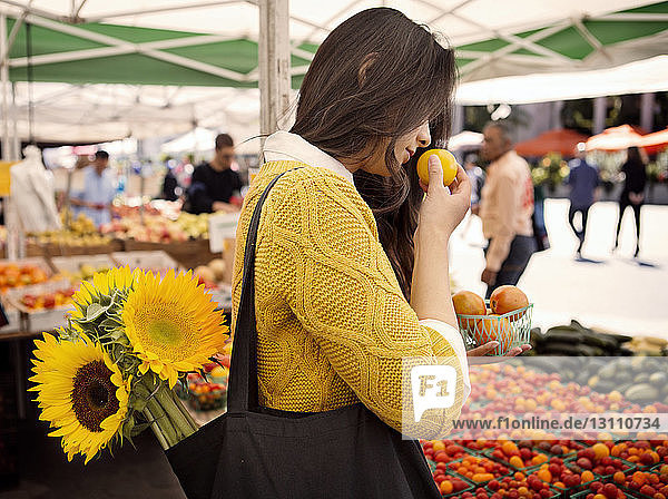 Woman smelling fruit at market stall