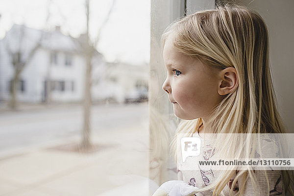 Close-up of girl sitting by window at home
