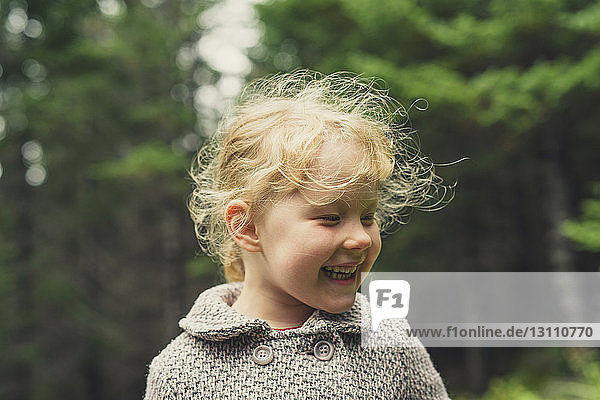 Fröhliches Mädchen mit blonden Haaren im Wald