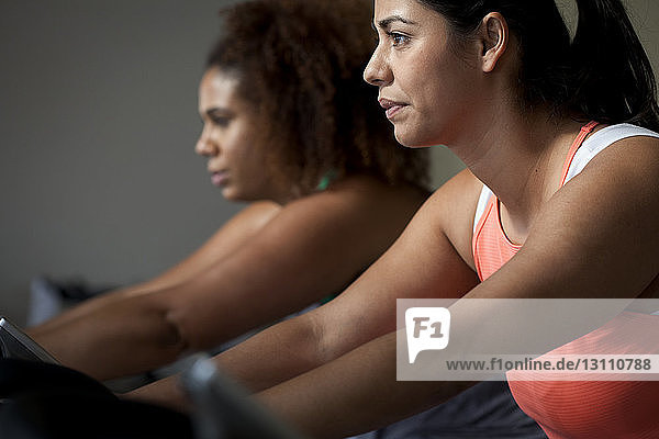 Freundinnen in Übergröße trainieren auf Heimtrainern im Fitnessstudio