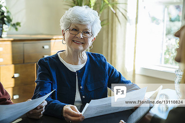 Ältere Frau schaut weg  während sie im Büro des Finanzberaters Dokumente in der Hand hält