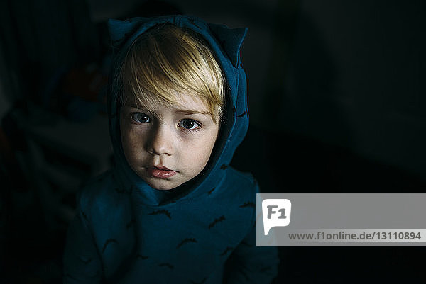 Hochwinkelporträt eines süßen Jungen mit Kapuzenhemd in der Dunkelkammer