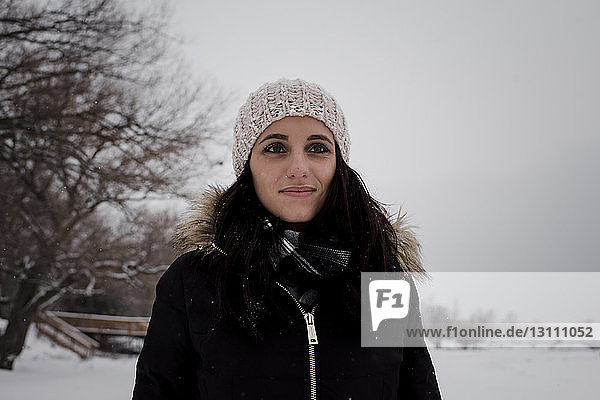 Smiling woman looking away while standing against sky during winter