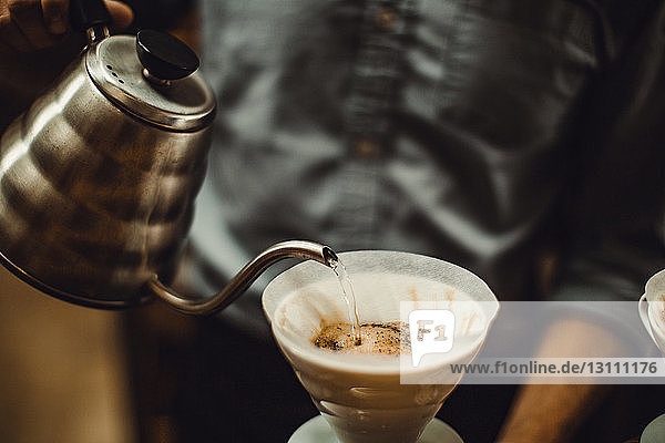 Barista gießt Wasser in den Kaffeefilter eines Cafés