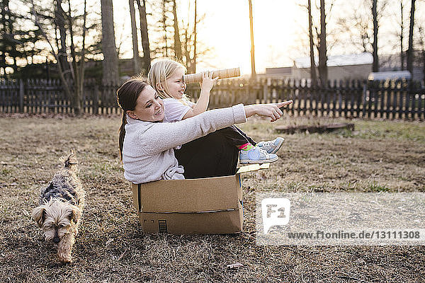 Mutter und Tochter sitzen in einem Pappkarton auf dem Feld