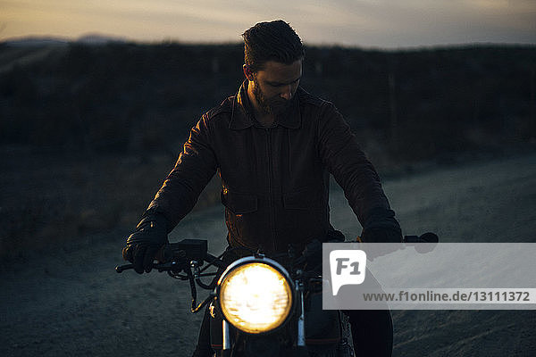 Man riding illuminated motorcycle on field