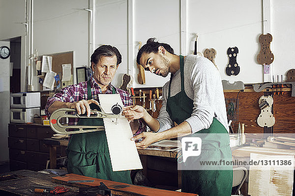 Arbeiter messen Brett mit Instrument beim Geigenbau in der Werkstatt
