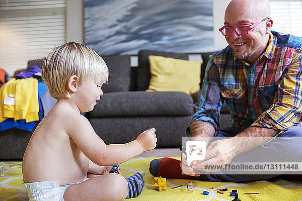 Father playing with boy on floor at home