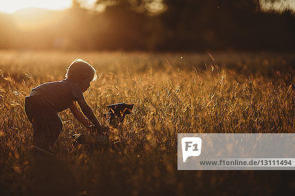 Side view of boy playing with toy earthmover on field
