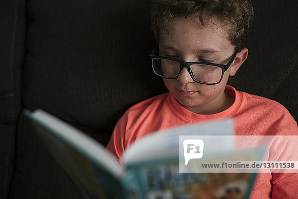 Nahaufnahme eines Jungen  der eine Brille trägt  während er zu Hause auf dem Sofa lernt