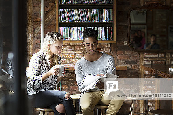 Man showing papers to woman while sitting at cafe