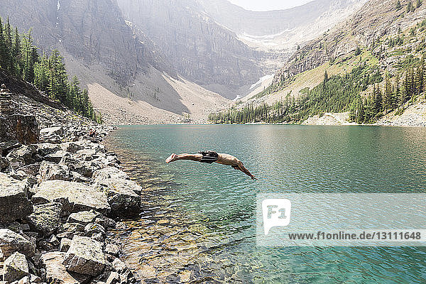 Side view of man diving in lake against mountains at Banff National Park
