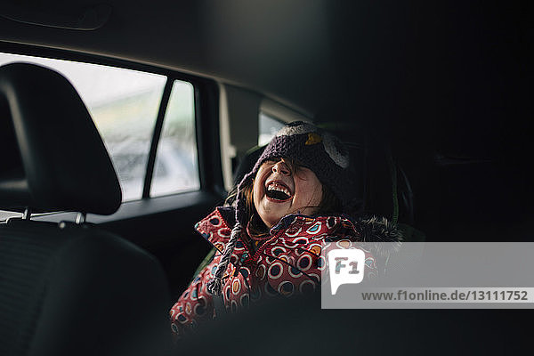 Fröhliches Mädchen lacht  während sie im Auto sitzt