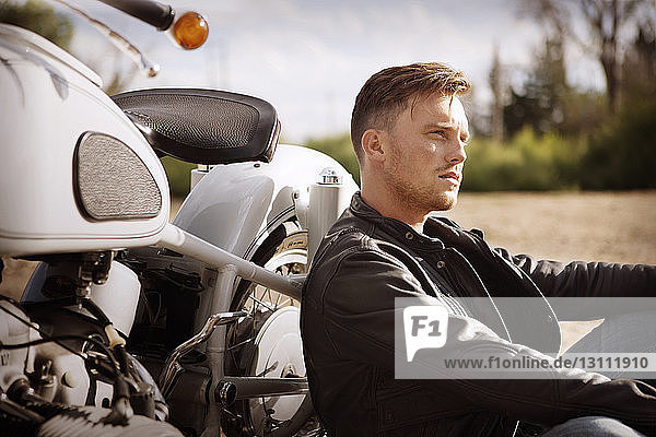 Nachdenklicher Mann lehnt auf Motorrad