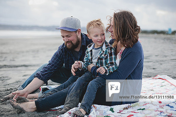 Happy family sitting at beach during sunset