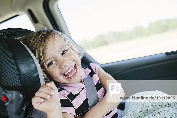 Porträt eines fröhlichen Mädchens im Auto sitzend