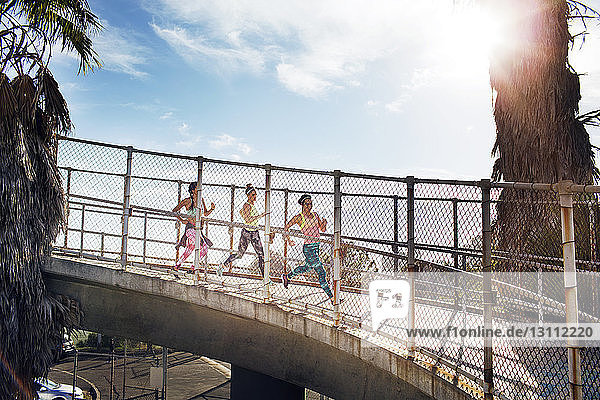 Joggerinnen auf der Brücke gegen den Himmel an einem sonnigen Tag