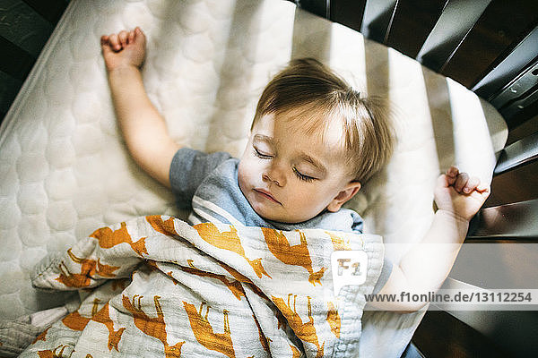 Draufsicht auf ein süßes Baby  das zu Hause im Gitterbett schläft