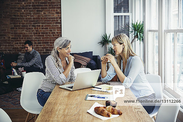 Businesswomen discussing at conference table in creative office