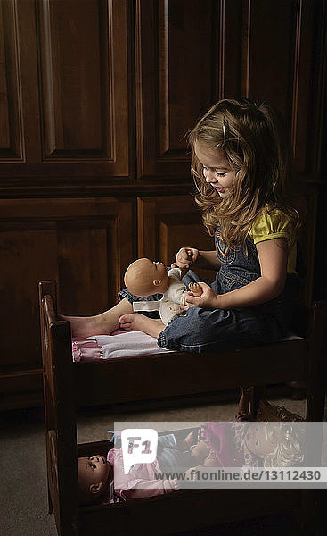 Mädchen in voller Länge spielt zu Hause mit Puppe