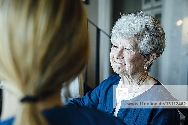Glückliche ältere Frau schaut auf häusliche Pflegekraft