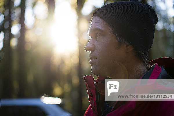 Close-up of thoughtful hiker looking away while standing in forest