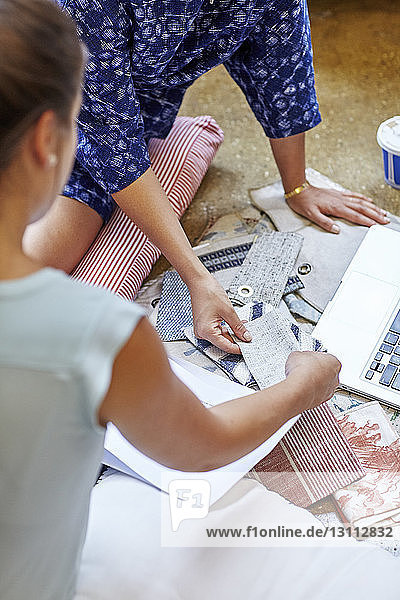 Cropped image of interior designers choosing curtain samples while sitting in workshop