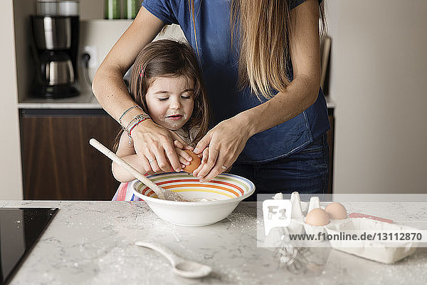 Mittendrin Mutter hilft Tochter bei der Zubereitung von Essen auf Kücheninsel zu Hause