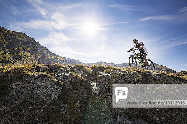 Low angle view of mountain biker riding bicycle against sky