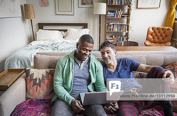 High angle view of homosexual males using laptop on sofa at home